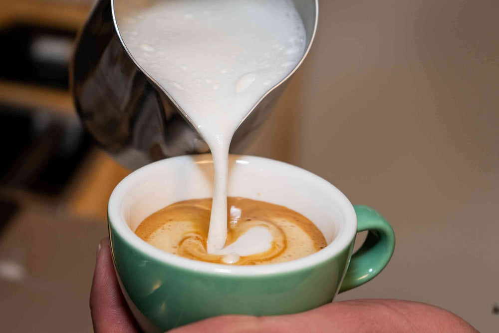 Das Bild zeigt die kunstvolle Zubereitung eines cremigen Cappuccinos